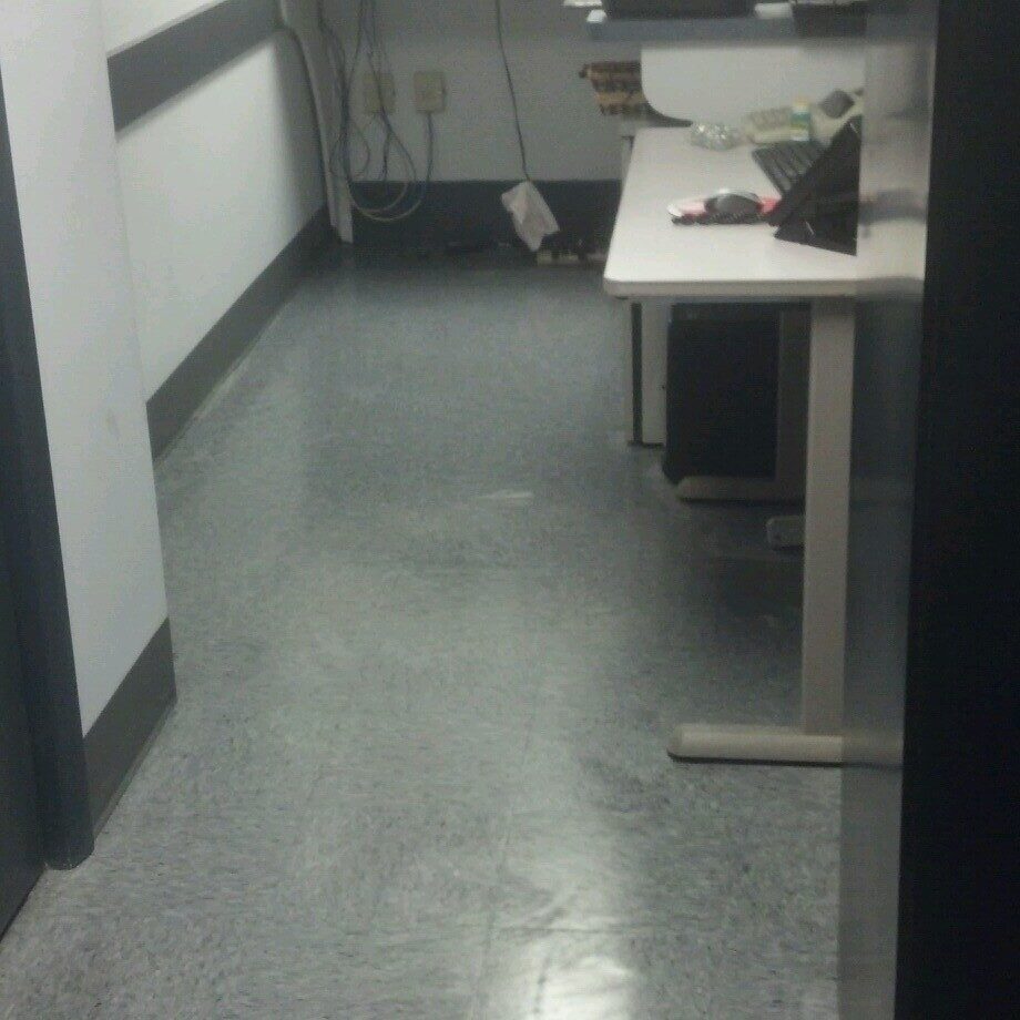 A freshly cleaned commercial corridor with a light vinyl floor, painted skirting boards and a wall bench