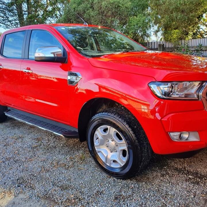 A freshly finished red ute with a mirror-gloss paint job parked on a gravel driveway